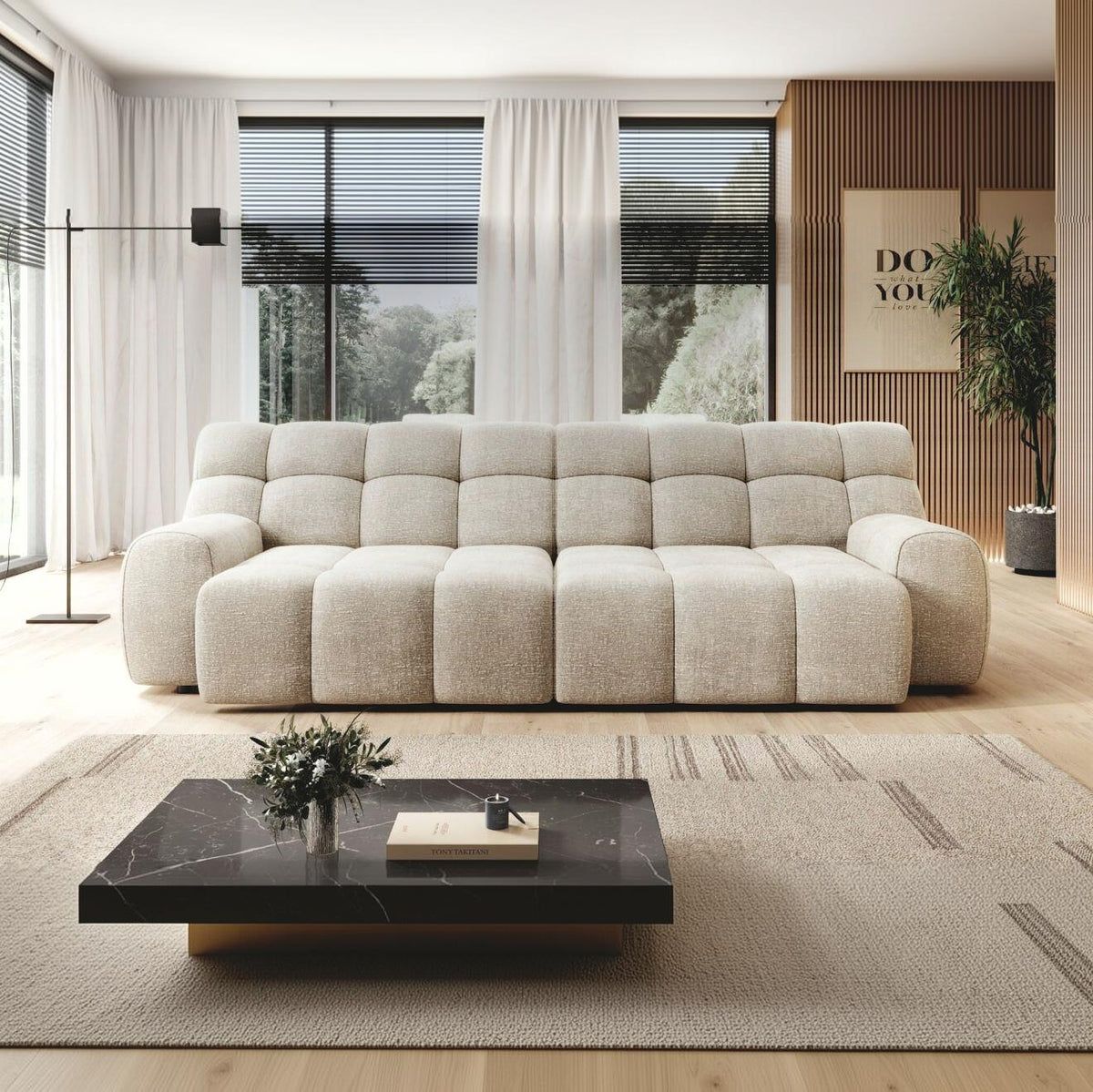 A modern beige sectional sofa in a bright, contemporary living room with large windows, a black marble coffee table, and a light rug.