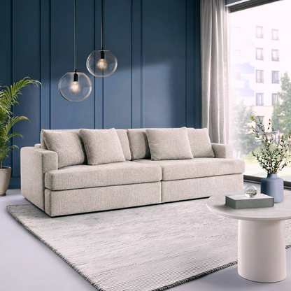 A  grey-beige fabric sofa bed, styled in a modern living room with a woven area rug, wooden wall.