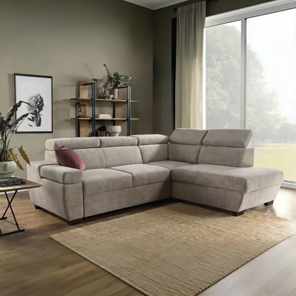 A beige fabric sectional sofa with a right-facing chaise lounge, styled in a modern living room with a brown rug, wooden floor, and a large window.